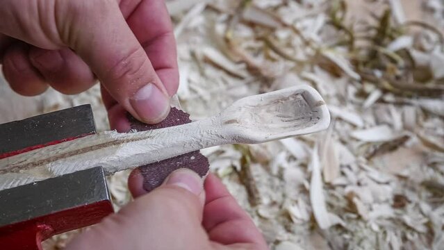 Filmmaterial von einem Holzl&ouml;ffel schnitzen mit Schleifpapier auf einer Werkbank mit Holzsp&auml;ne, Deutschland