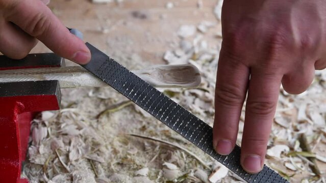 Footage of a wooden spoon carving with wood rasp on a workbench with wood chips, Germany