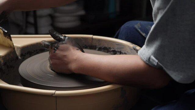 Anonymous people using pottery wheel and sculpting clay in pottery studio. Young people mold clay for product. Concept of education, business, art talent and creative handmade.