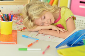 Cute schoolgirl sleeping at her homework at home