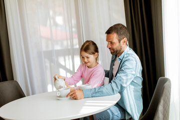 Father and daughter drinking tea together at the room