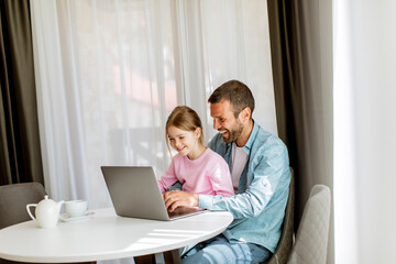 Father and daughter using laptop computer together