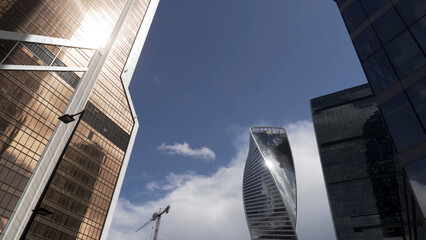 Bottom view of the glass skyscrapers of the business district against blue cloudy sky. Action....