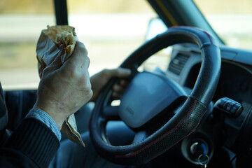 Closeup of a hand with a snack wrapped in a paper.