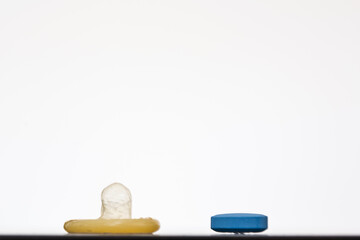 Blue pill and a condom on a white background; concept of using a medicine to solve a problem such as male erectile dysfunction
