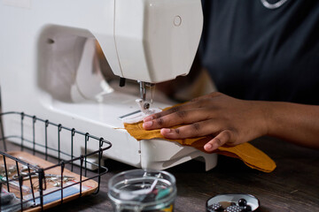 Hand of young black woman creating part of new fashionable piece of clothing while using electric...