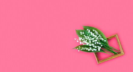 Greeting card for mother's day with bouquet of tender lilies of the valley with wooden frame  on  pink background.