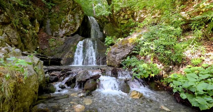 Fairy waterfall at wild forest. Wonderful fresh water waterfalls river flowing. Forest rocks with a roaring stream running. Panoramic sun landscape of nature waterfall. Fresh nature. Loop video. 4K