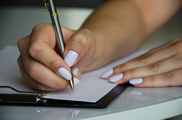 the girl signs a contract, a contract. the girl's hand holds the pen and puts a signature on the document.