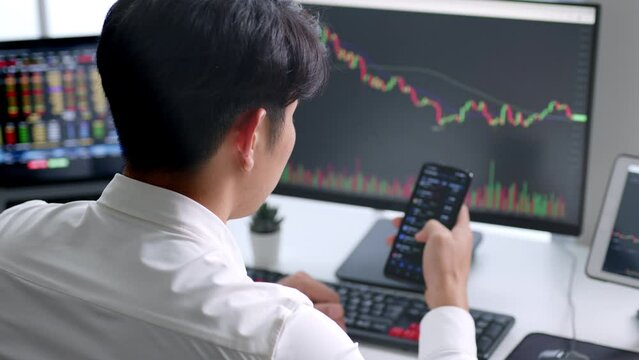 Young Asian investor watching the change of cryptocurrency and stock market on smartphone.
