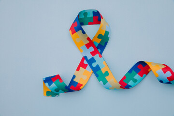 World Autism awareness and pride day with Puzzle pattern ribbon on blue background