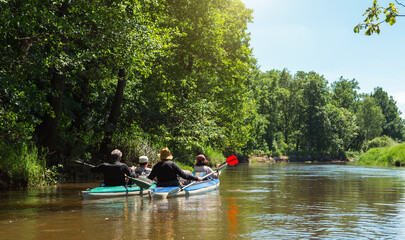 Family kayak trip. Man and woman and elderly couple senior and seniora rowing boat on the river, a...