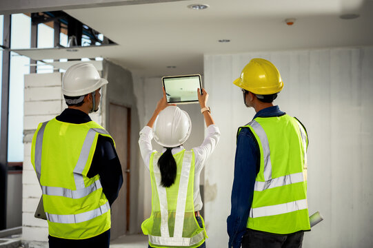 Construction Engineer team uses tablets to take photo and record data while inspecting construction work,  Checking to light on ceiling and other systems above ceiling