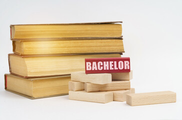 On a white surface, a stack of books and wooden blocks, on a red block there is an inscription - Bachelor