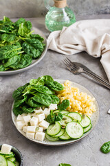 Bowl with pasta, cucumber, cheese and spinach on the table. Vertical view. Close-up