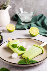 Vegetarian popsicle made from matcha tea, coconut milk and mint on a plate. Vertical view. Close-up