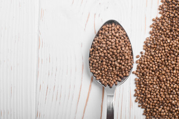 Soya grains in a spoon on a white wooden background
