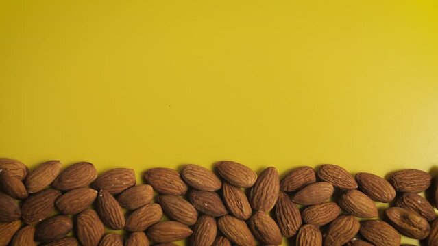 Lot of almond nuts falling from above on a yellow background. Flatley stop motion animation