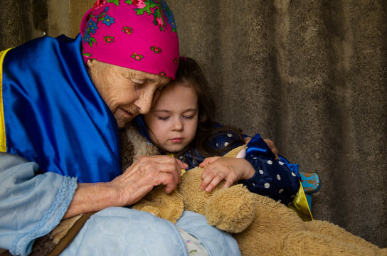 A grandmother with a child hides in the basement during the war. The child is wrapped in a Ukrainian flag in a bomb shelter. War in Ukraine. Stop war. A woman with a child in a bomb shelter. 
