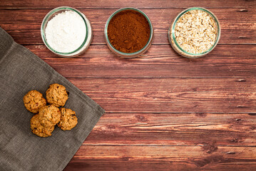 Preparation of homemade cookies with ingredients on dark wooden background. Homemade food concept with top view, space for text.