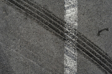 Asphalt texture with white line and tire marks. Smooth asphalt road. Tarmac dark grey grainy road background.Top view - 502098567