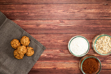 Preparation of homemade cookies with ingredients on dark wooden background. Homemade food concept with top view, space for text.