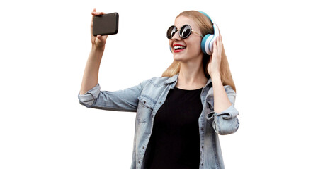 Portrait of happy smiling young woman taking selfie picture by smartphone in wireless headphones listening to music isolated on white background