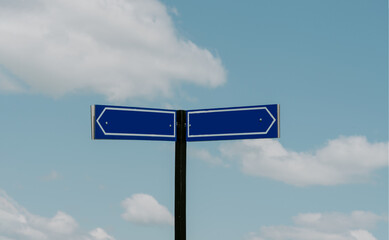 Blank sign crossroads post with sky and fluffy clouds on the background