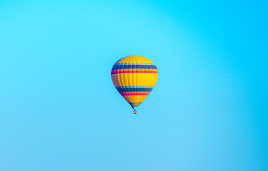 Colorful balloon flying over a clear blue sky during a sunset on a sunny day, copy space