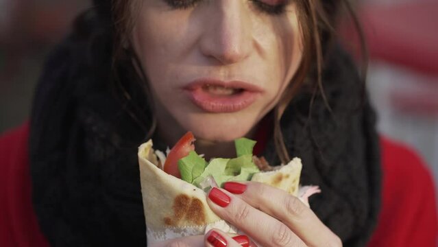 Young girl eats shaurma gyros close-up