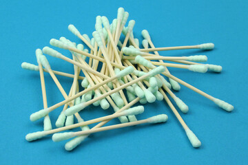 Cotton ear buds, wooden stick. Ear cleaner - Pile of green cotton buds. Set of ear cotton sticks on blue background