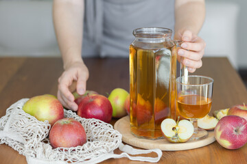 Young woman and fresh homemade organic apple juice or cider on a wooden table in a glass jug