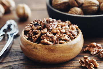 Shelled walnuts, nutcracker and bowl of nuts on kitchen table.