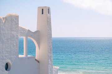Top of a white Mediterranean house with the turquoise sea in the background.
