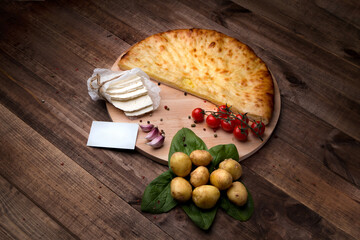 Ossetin pie on a wooden table with vegetables