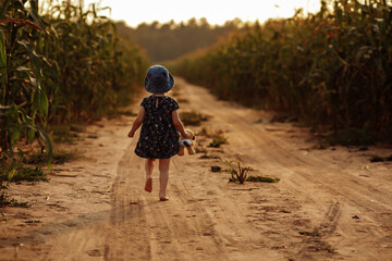 Charming little girl runs along a field road.