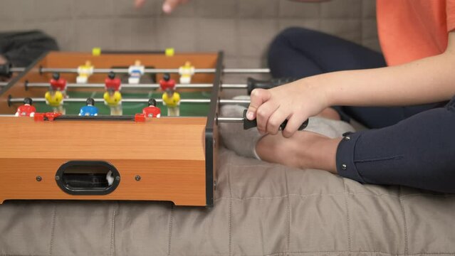 Football with miniature players. Twi little girls play football with miniature players on the board in the room.