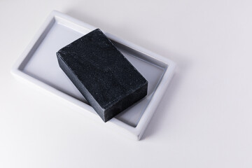 Natural organic hand cut charcoal soap bar on white background with copy space.