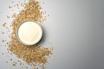 Scattered oat flakes on white background with milk in the bowl.
Oat flakes isolated on white background. Healthy food concept. Energy breakfast.