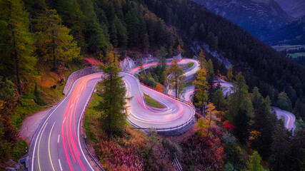 Maloja pass, Switzerland. A road with many curves among the forest. A blur of car lights. Landscape...
