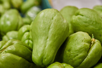 Green chayotes placed on a shelf for sale inside a market
