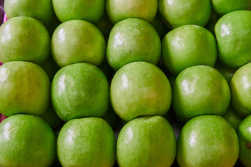 Green apples placed on a shelf for sale in a market