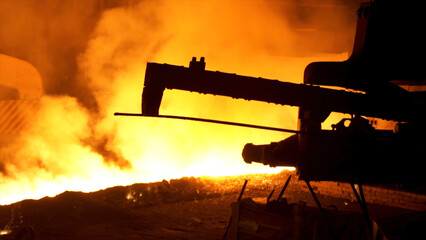 Molten metal pouring from the special mechanism, metallurgy concept. Molten steel flowing in...