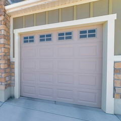 Square Three car garage exterior with stone veneer and green board and batten siding