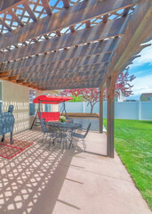 Vertical Backyard patio with attached wooden pergola roof and covered barbecue griller