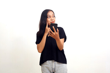 Asian woman standing, holding a cell phone while looking sideways. Isolated on white