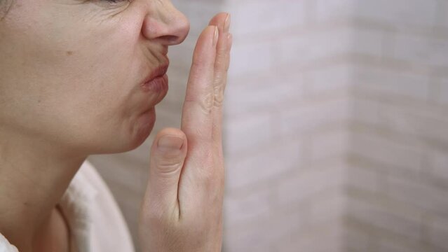 Spray for bad smell. A woman feel bad smell from her mouth and use spray at home.