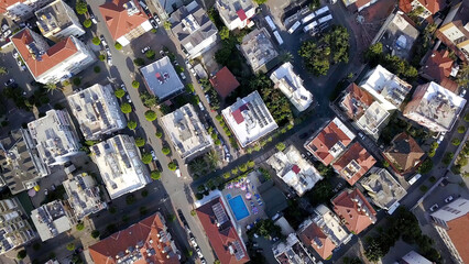 Top view of roofs and streets of city in summer. Clip. Beautiful southern city with orange roofs, high-rise buildings and green vegetation. Resort town for summer holidays