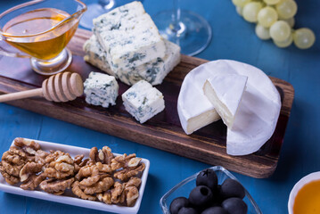appetizer cheese dor blue and camembert on a wooden board with honey and grapes
