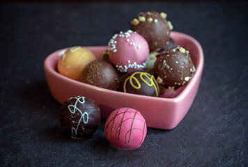 pink heart full of truffles with selective focus on the candies close up